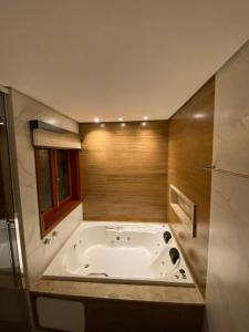 baño con bañera grande y ventana en Apartamento Avenida en Camanducaia