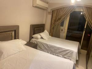 two beds in a hotel room with a window at Apartment for rent Zamalek in Cairo