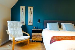 布鲁日兰花旅馆的一间卧室配有一张床、一张白色椅子和一把椅子