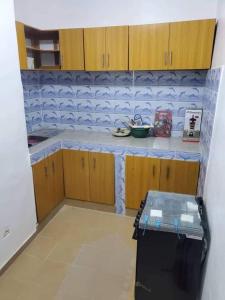 a kitchen with wooden cabinets and a counter top at Timba chic-Allada in Allada