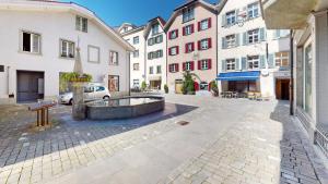 a courtyard with a fountain in the middle of buildings at Solution-Grischun - Altstadtwohnung - Zentral - Boxspringbett - Dachterrasse - Kaffe&Tee in Chur