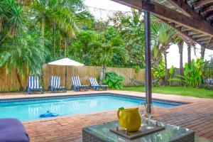 a swimming pool with chairs and a table with a wine glass at Dreampoolhousemiami in Miami