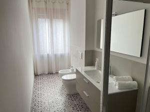 a white bathroom with a toilet and a sink at Casa Marconi - City Center in Bra