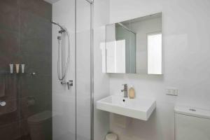 a white bathroom with a sink and a shower at The Wave in Newcastle