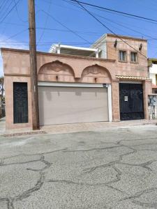 a building with a white garage door on a street at BEAUTIFUL AND COZY WITH TERRACE, GREAT LOCATION in Mexicali