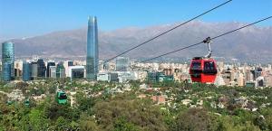 um teleférico vermelho sobrevoando uma cidade em Hotel Presidente em Santiago