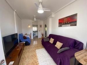 a living room with a purple couch and a tv at Saint James park 2 dormitorios in Orihuela
