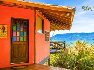 a red house with a door and a view of the water at Bangalô Ilhabela in Ilhabela