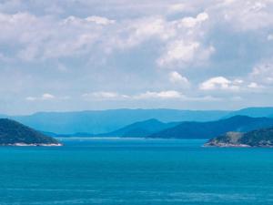 a view of the ocean with mountains in the background at Bangalô Ilhabela in Ilhabela