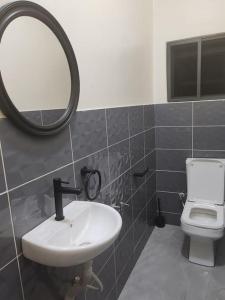 ein Badezimmer mit einem Waschbecken, einem Spiegel und einem WC in der Unterkunft Le Leo Lodge in Lomé