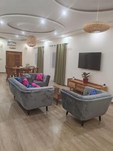 ein Wohnzimmer mit 2 Sofas und einem TV in der Unterkunft Le Leo Lodge in Lomé
