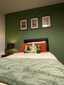 ein Schlafzimmer mit einer grünen Wand und einem Bett mit Kissen in der Unterkunft St James 3 bedroom House in Tunbridge Wells in Royal Tunbridge Wells