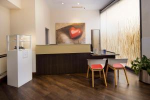 una sala de espera con 2 sillas y una pintura del corazón en Best Western Plus City Hotel en Génova