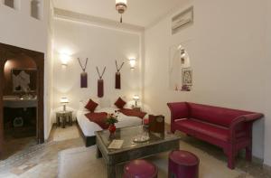 un soggiorno con letto e divano rosso di Riad Pachavana a Marrakech
