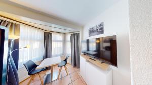 Zimmer mit einem Schreibtisch, einem TV sowie einem Tisch und Stühlen. in der Unterkunft Etagenbett - Küche - Kaffee - Tee - 55" Smart TV in Chur