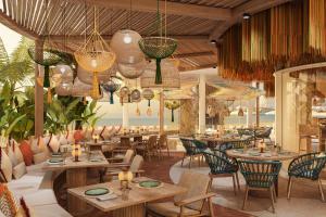 een restaurant met tafels en stoelen en kroonluchters bij The St Regis Al Mouj Muscat Resort in Muscat
