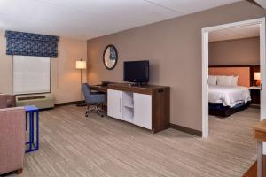 a hotel room with a bed and a desk with a television at Hampton Inn Emporia in Emporia