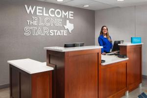 a woman standing at a welcome to the lone star state office at Hampton Inn & Suites El Paso-Airport in El Paso