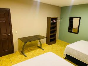 a room with a bed and a table and a mirror at La Casita in San Pedro Sula