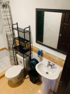 a bathroom with a toilet and a sink and a mirror at La Casita in San Pedro Sula