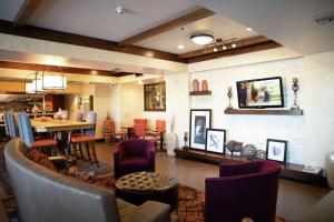 Hampton Inn & Suites Fresno في فريسنو: غرفة معيشة مع طاولة وكراسي