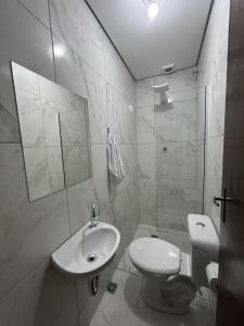 a white bathroom with a toilet and a sink at Pousada Recanto Da Fé in Aparecida