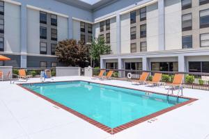 a swimming pool with chairs and a building at Hampton Inn Florence Midtown near University of North Alabama in Florence