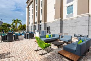 Hampton Inn & Suites Fort Myers-Colonial Boulevard في فورت مايرز: فناء به اثاث وطاولات ومبنى