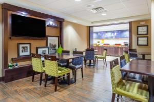 une salle à manger avec des tables et des chaises et une télévision à écran plat dans l'établissement Hampton Inn Sioux Falls, à Hayward Addition