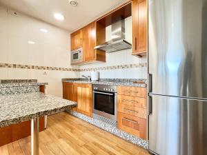 a kitchen with wooden cabinets and a stainless steel refrigerator at Coruña House in A Coruña
