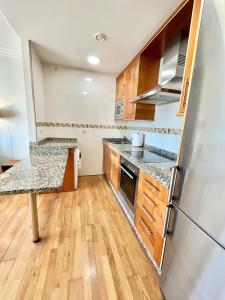 eine Küche mit Holzschränken und einem Kühlschrank in der Unterkunft Coruña House in A Coruña