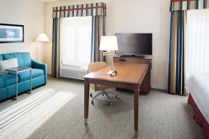 Habitación de hotel con escritorio, TV y sofá. en Hampton Inn & Suites - Mansfield, en Mansfield