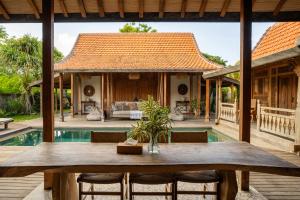 Un comedor al aire libre con una mesa y una casa. en The Padang Villa Jungle Escape 5 mins drive from Uluwatu's Beaches, en Uluwatu