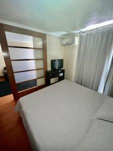 サンティアゴにあるDepartamento con ubicacion perfecta en las condesのベッドルーム(白いベッド1台、テレビ付)
