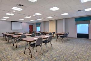 una sala de conferencias con mesas, sillas y una pantalla en Hampton Inn Fayetteville, en Fayetteville