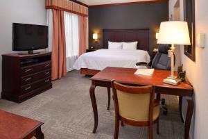 Habitación de hotel con cama, escritorio y TV. en Hampton Inn & Suites Greenville, en Greenville