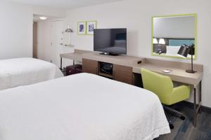 a hotel room with two beds and a desk with a television at Hampton Inn - Greenville in Greenville +22 photos
