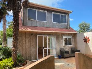 a house with a palm tree in front of it at Oneroa Chalet in Oneroa