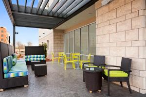a patio with chairs and tables and yellow chairs at Home2 Suites by Hilton Greensboro Airport, NC in Greensboro