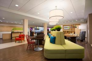 a lobby with a couch and a table and chairs at Home2 Suites by Hilton Greensboro Airport, NC in Greensboro