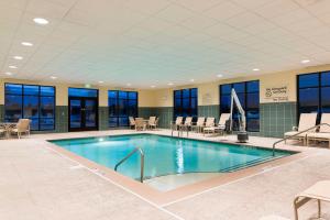 uma piscina no átrio do hotel com cadeiras e mesas em Hampton Inn & Suites Hartford-Manchester em Manchester