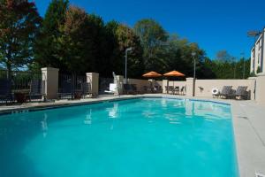 ein großer blauer Pool mit Stühlen und Sonnenschirmen in der Unterkunft Hampton Inn Gainesville in Gainesville