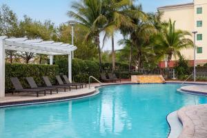 a large swimming pool with chairs and a canopy and palm trees at Hampton Inn & Suites Homestead Miami South in Homestead