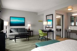 Hampton Inn & Suites Homestead Miami South في هومستيد: غرفة في الفندق بها سرير وأريكة ومكتب