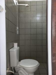 a bathroom with a toilet and a tiled wall at Excelentes Quartos com banheiros privativos in Recife