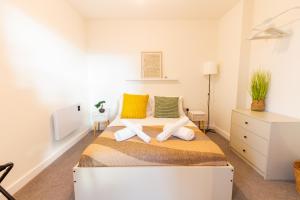 ein Schlafzimmer mit einem Bett mit gelben und grünen Kissen in der Unterkunft Bright & Cosy Penthouse in Old Trafford in Manchester
