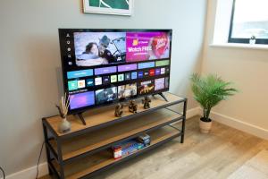 einen Flachbild-TV auf einem Stand in einem Wohnzimmer in der Unterkunft Bright & Cosy Penthouse in Old Trafford in Manchester