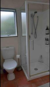 Un baño con inodoro y ducha con ventana. en Oneroa Chalet, en Oneroa