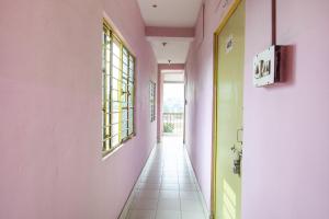 um corredor com paredes cor-de-rosa e verde e piso em azulejo branco em OYO Hotel Suvidha em Jamshedpur