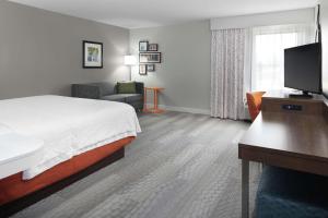 a hotel room with a bed and a desk with a television at Hampton Inn Jasper in Jasper